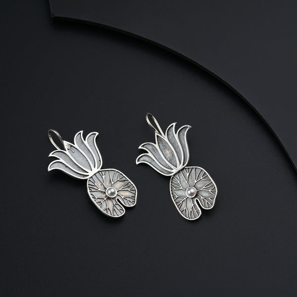 a pair of silver earrings on a black surface
