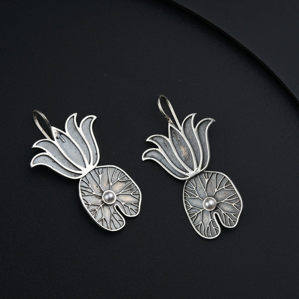a pair of silver earrings on a black surface