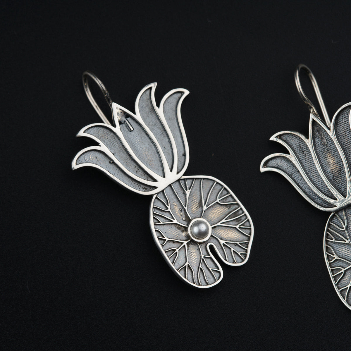 a pair of silver earrings with flowers on them