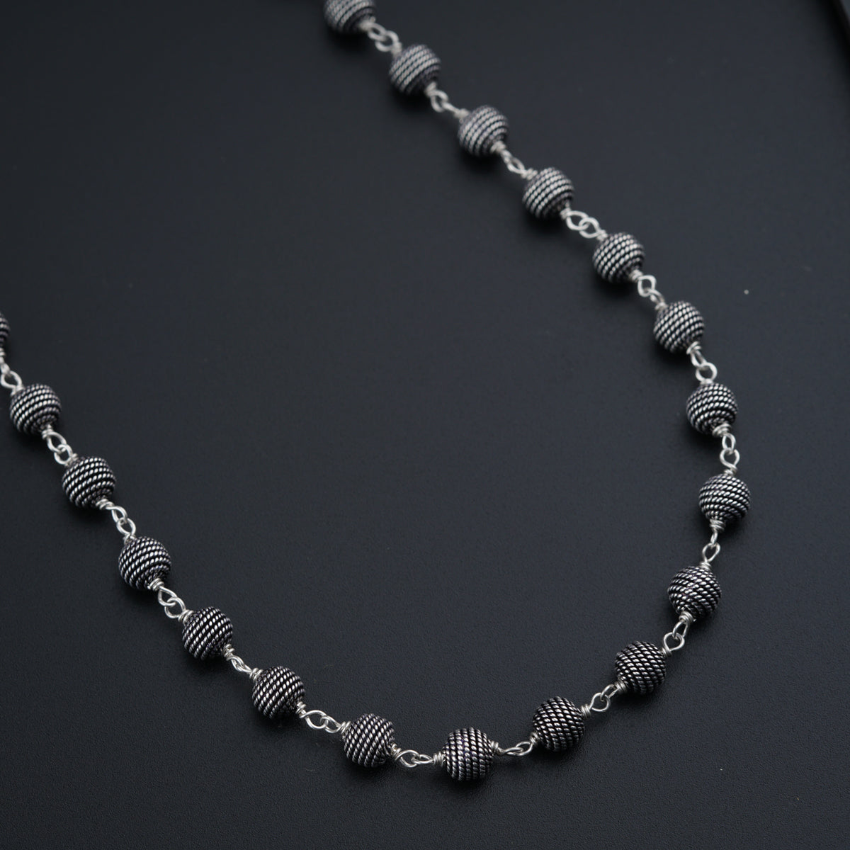a silver necklace with a knot on a black surface