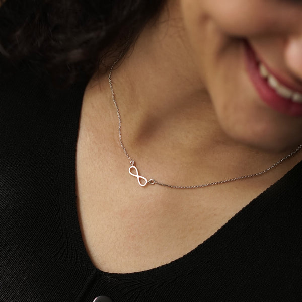Silver infinity pendant necklace on a woman's neck