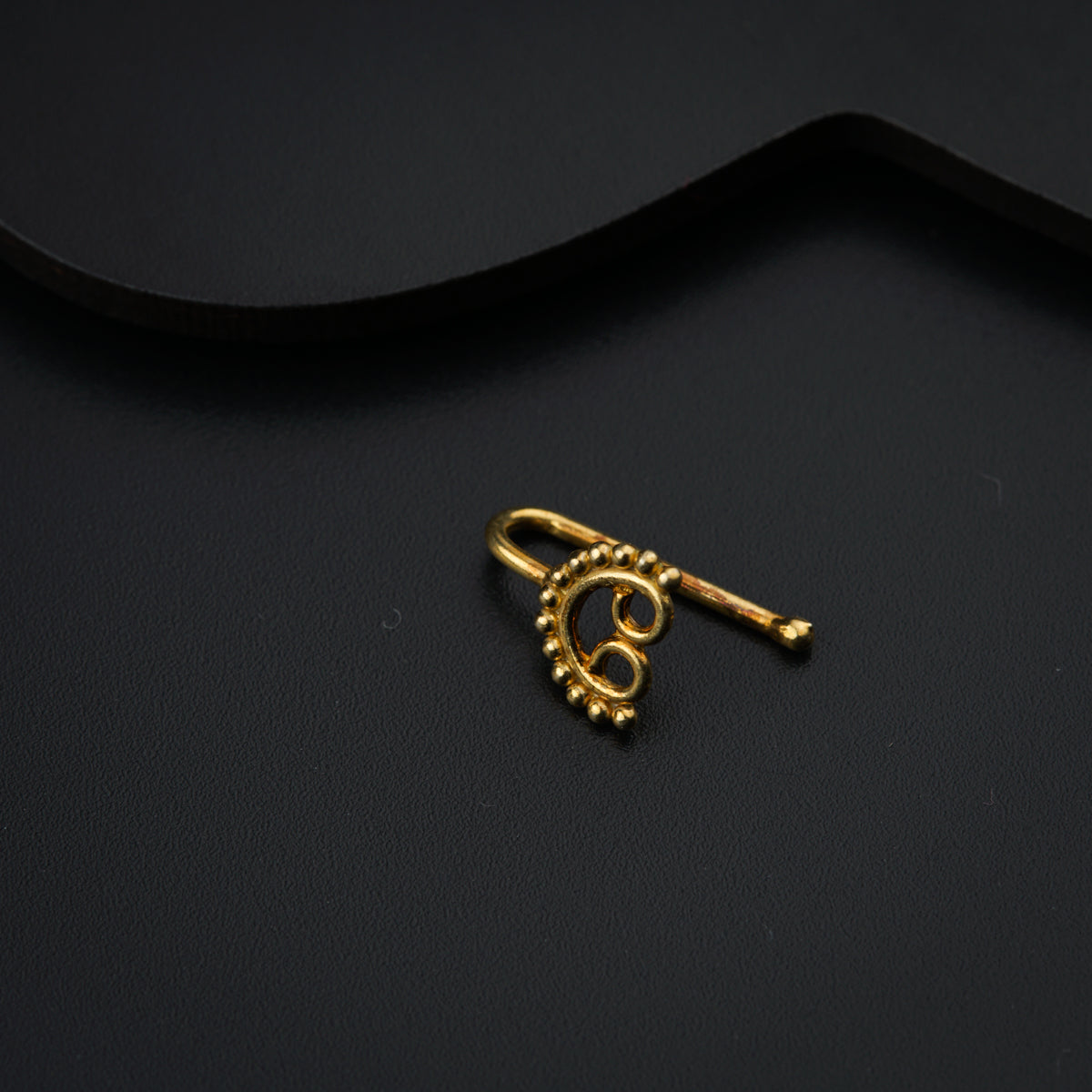 a gold brooch sitting on top of a black surface