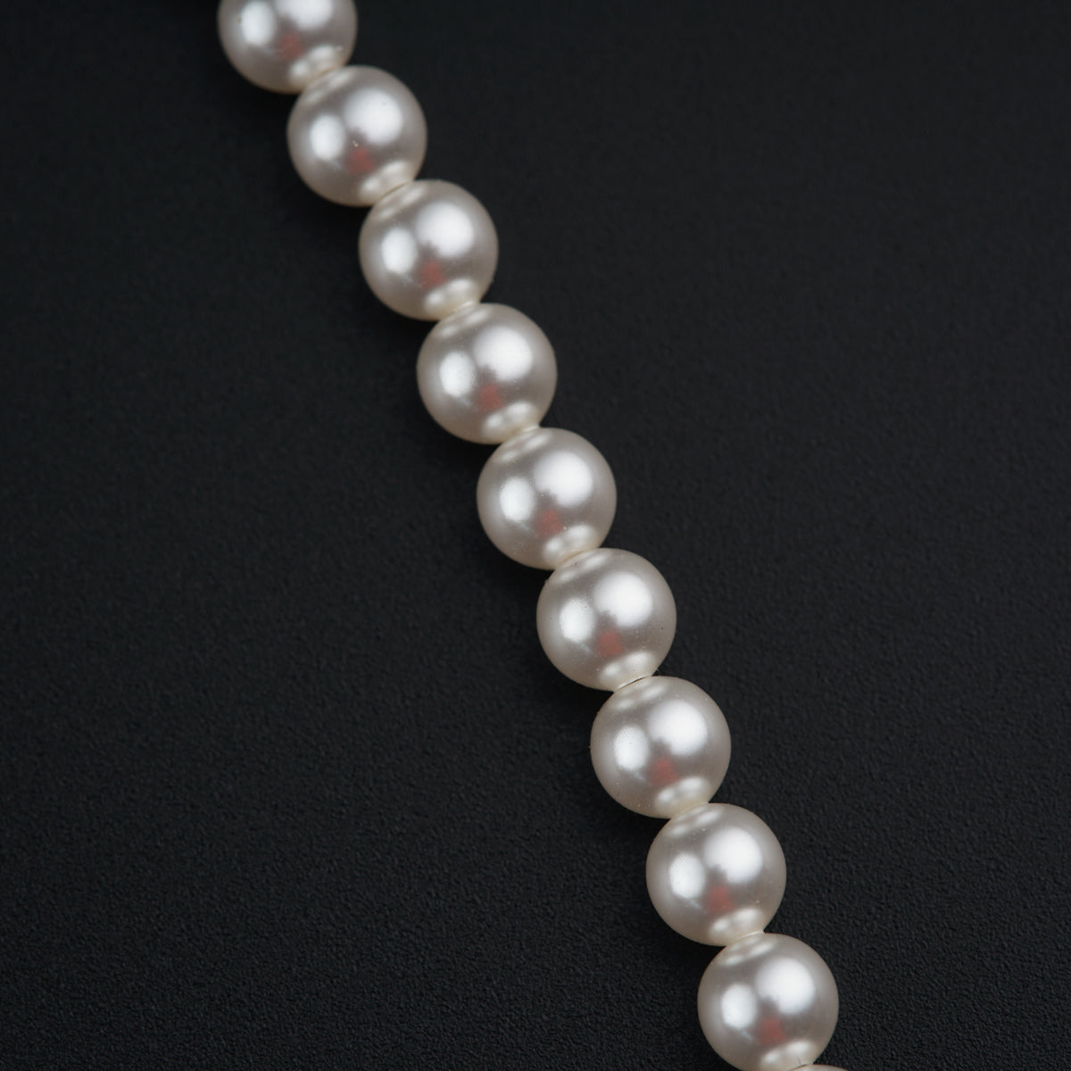 a long strand of white pearls on a black surface