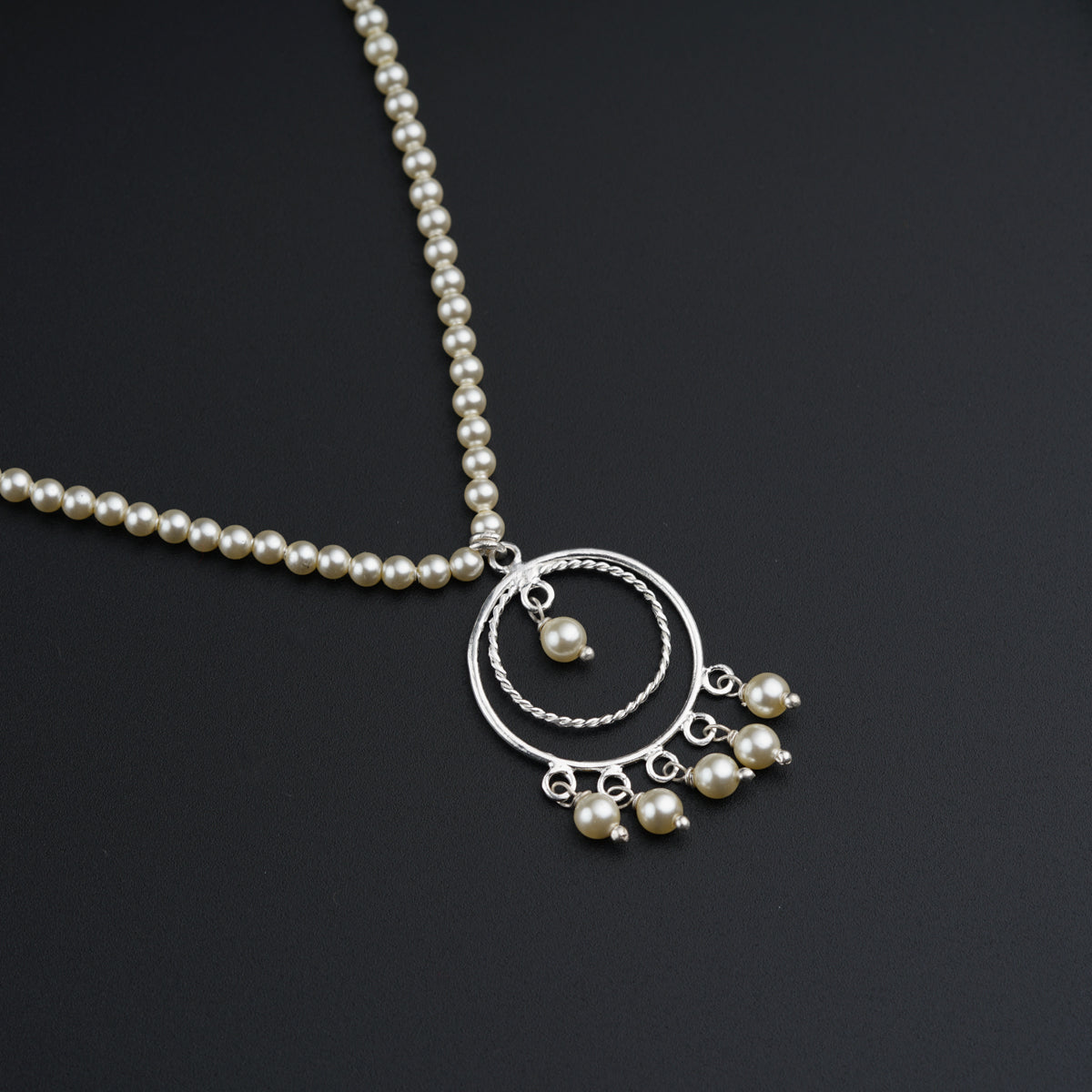 a necklace with pearls hanging from it on a black surface