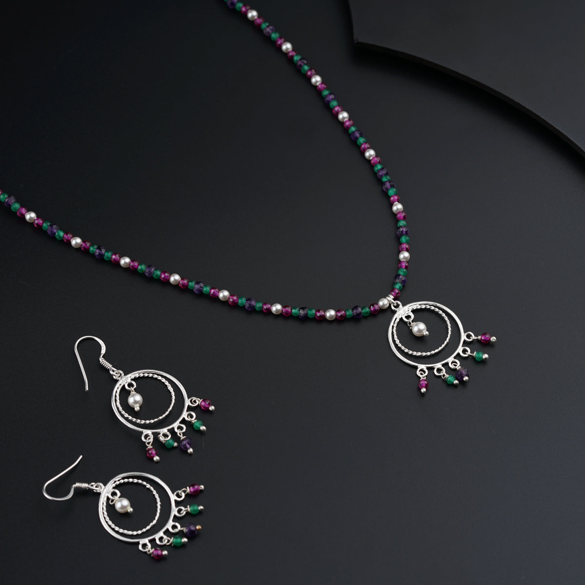 a necklace and earring set with beads on a black surface