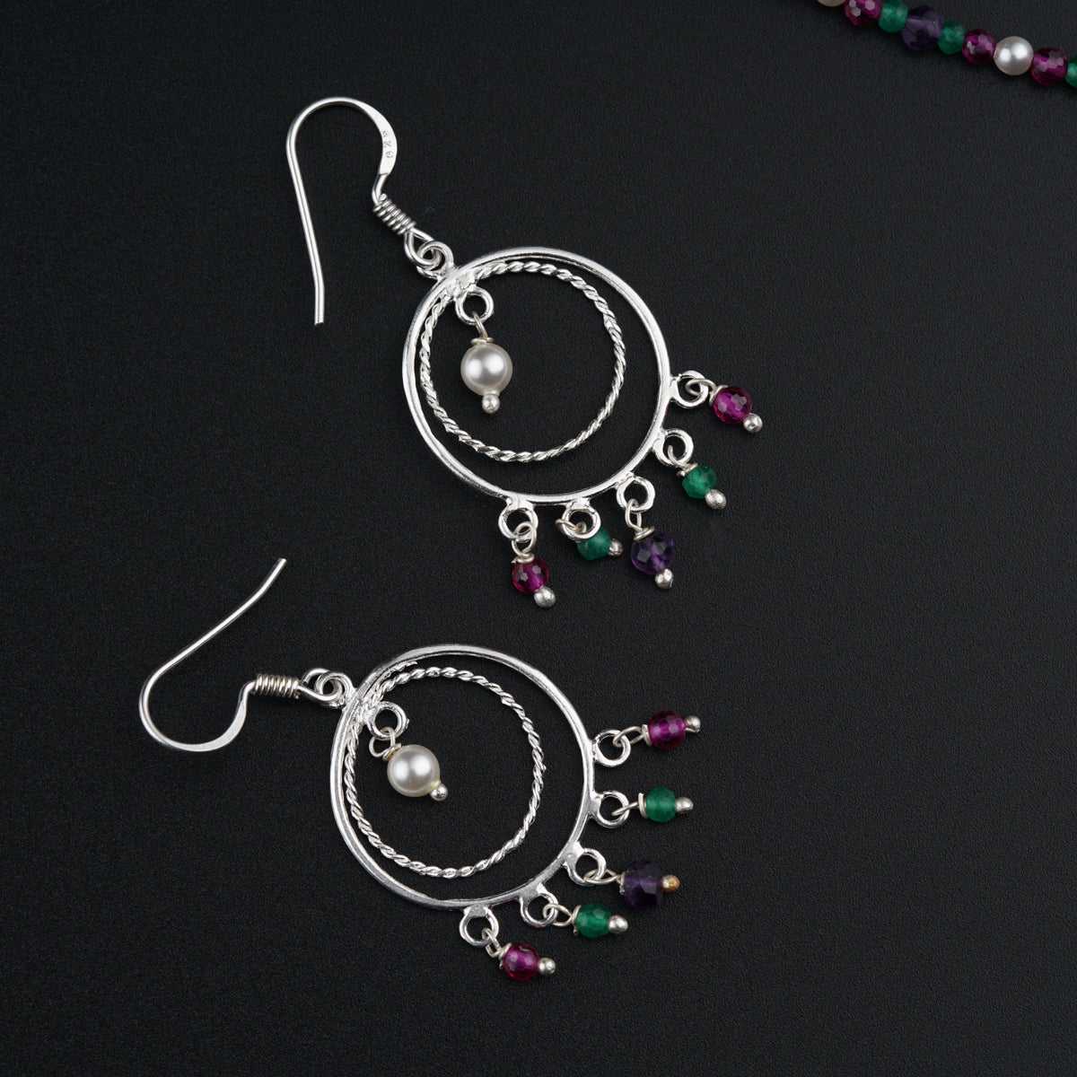 a pair of earrings with beads on a black surface