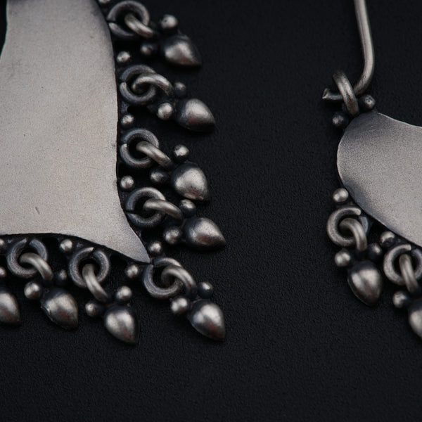 a pair of silver earrings on a black background
