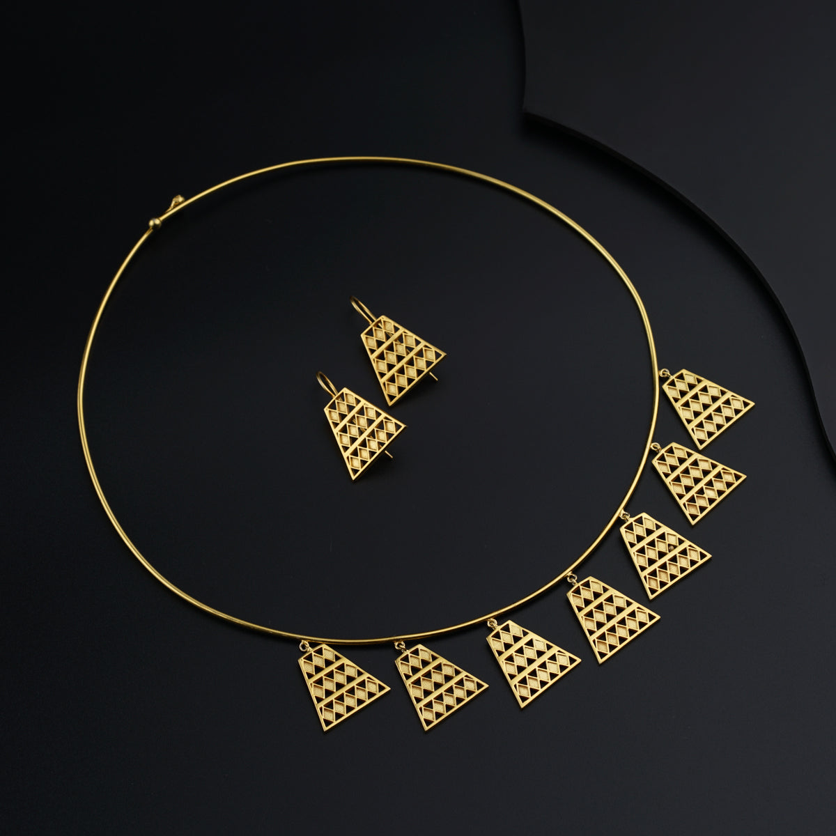 a gold necklace and matching earrings on a black background