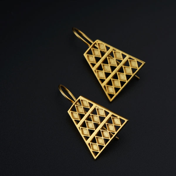 a pair of gold earrings on a black background