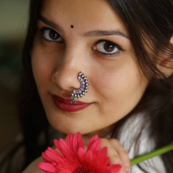 a woman with a nose piercing holding a flower