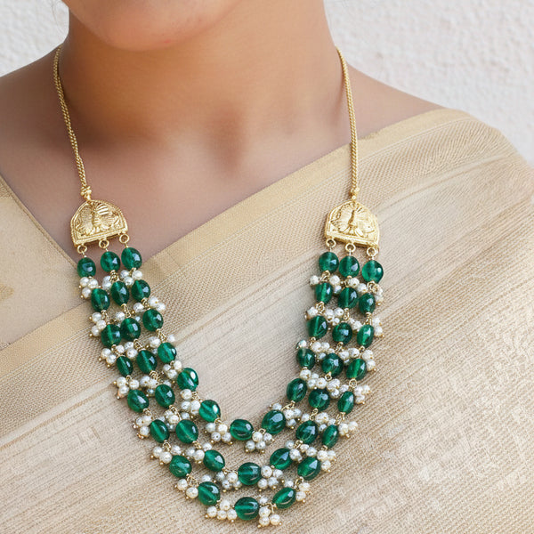 Gold necklace with green onyx and pearl accents worn on a woman