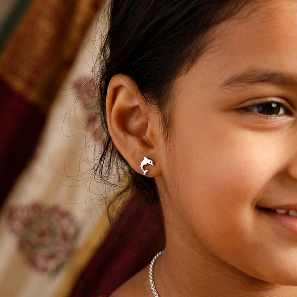 Close-up of woman wearing silver dolphin stud earrings