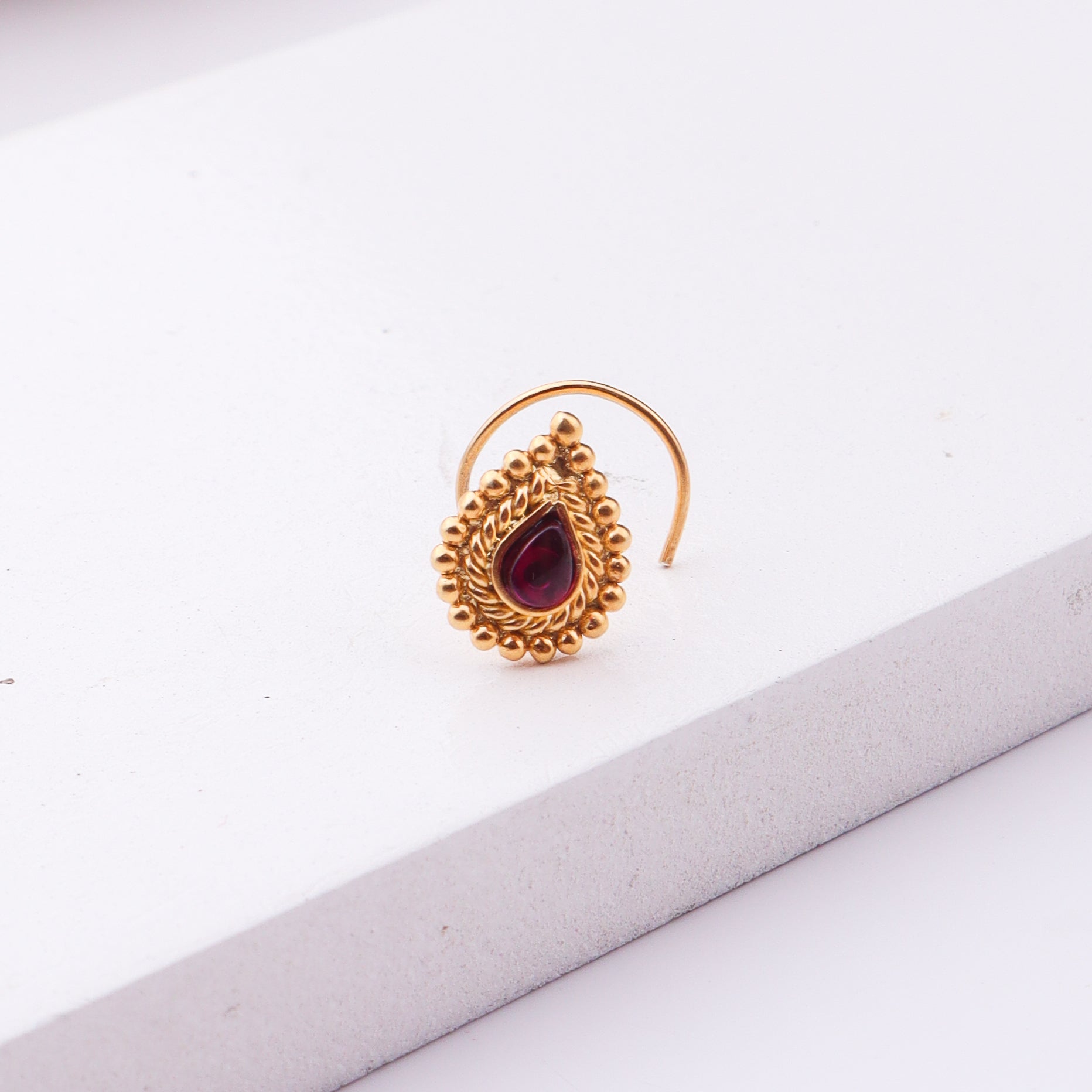 Gold-plated nose pin with red stone and intricate design for pierced noses