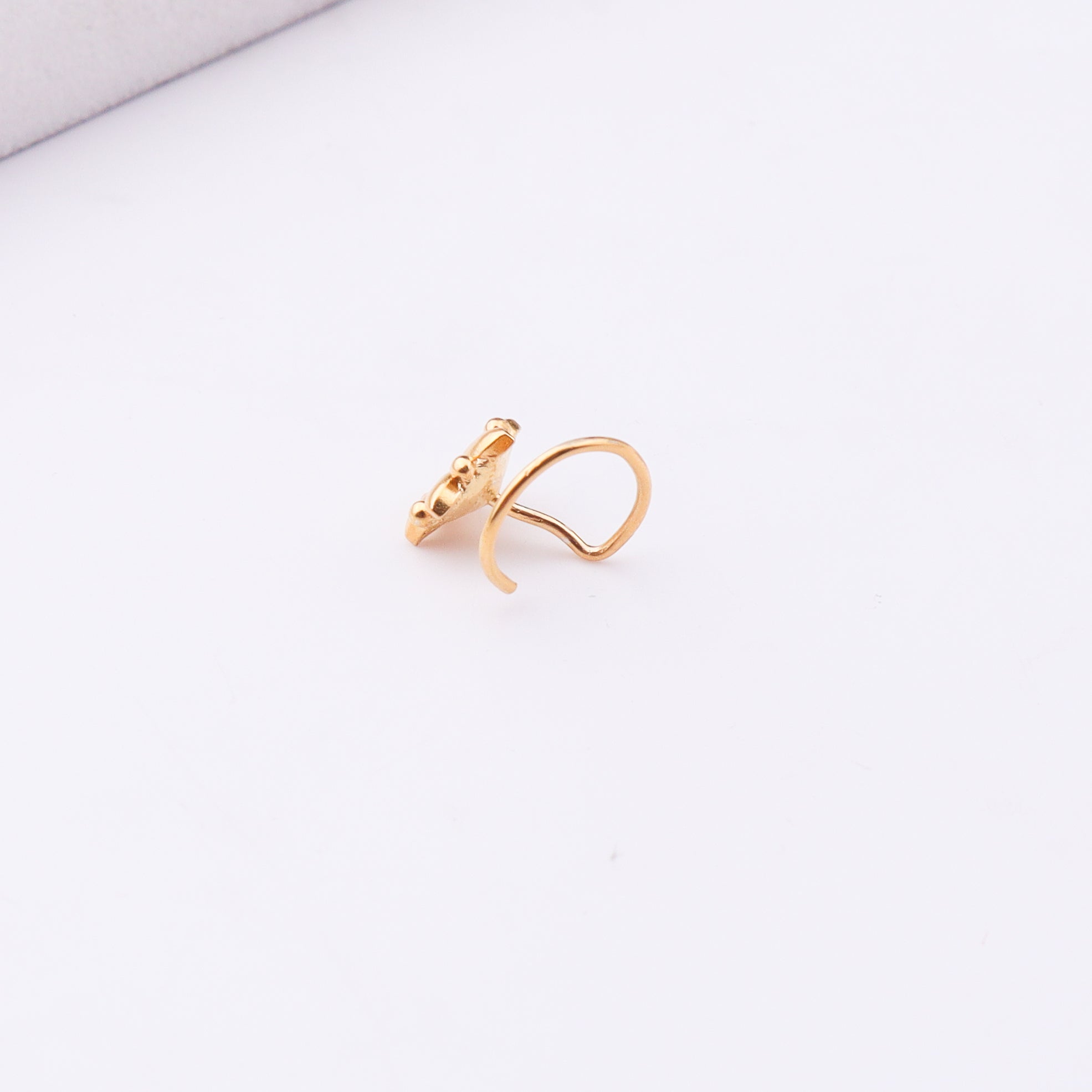 Gold plated nose pin with floral design on white background