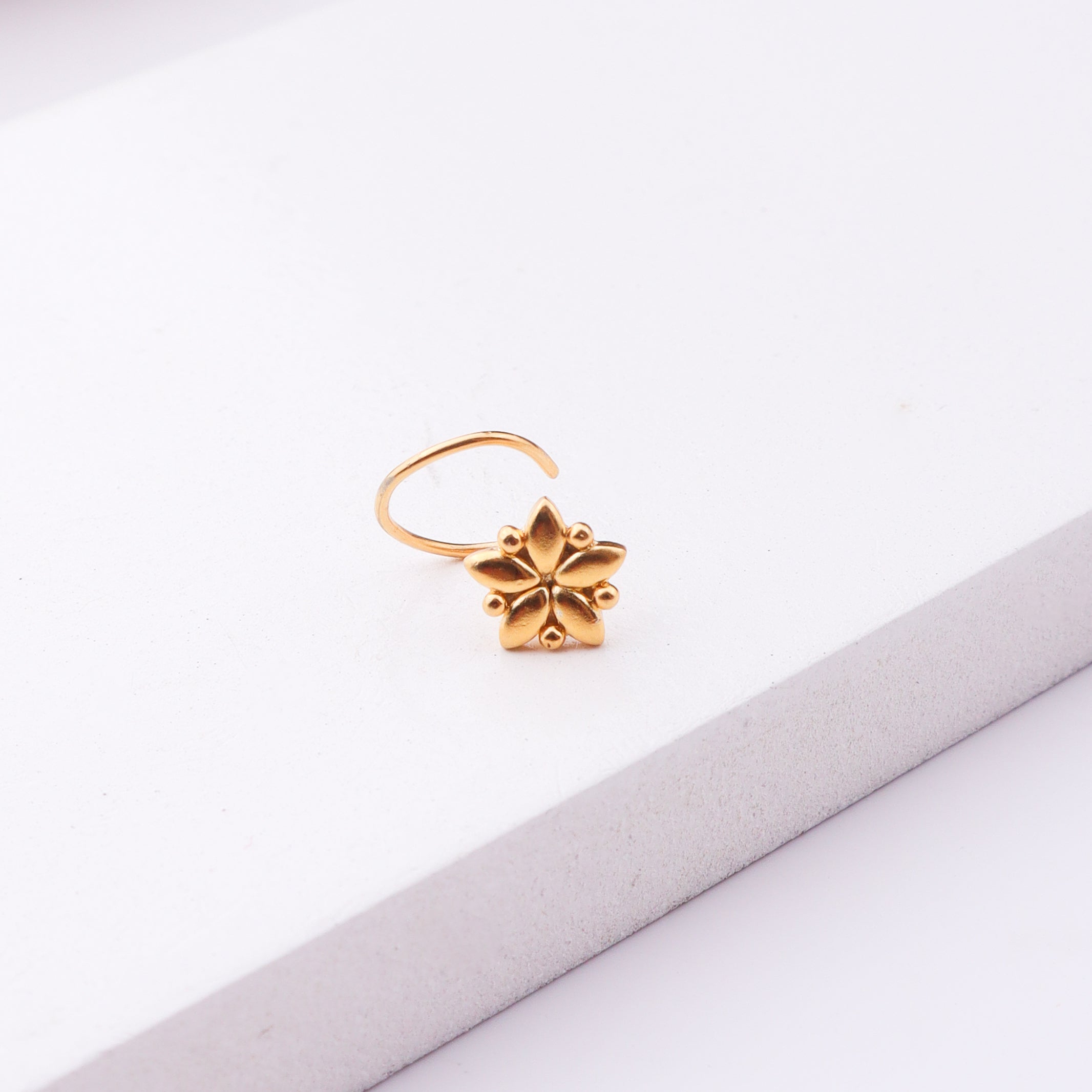 Gold floral nose pin on white background