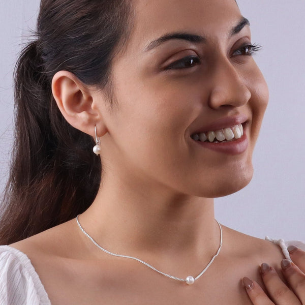 Woman wearing pearl silver jewelry set with necklace and earrings