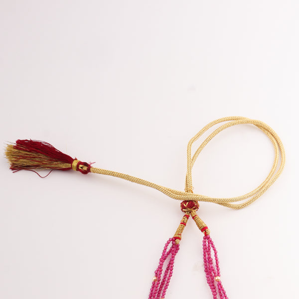 Close-up of pink beaded necklace with gold accents and carved pendant