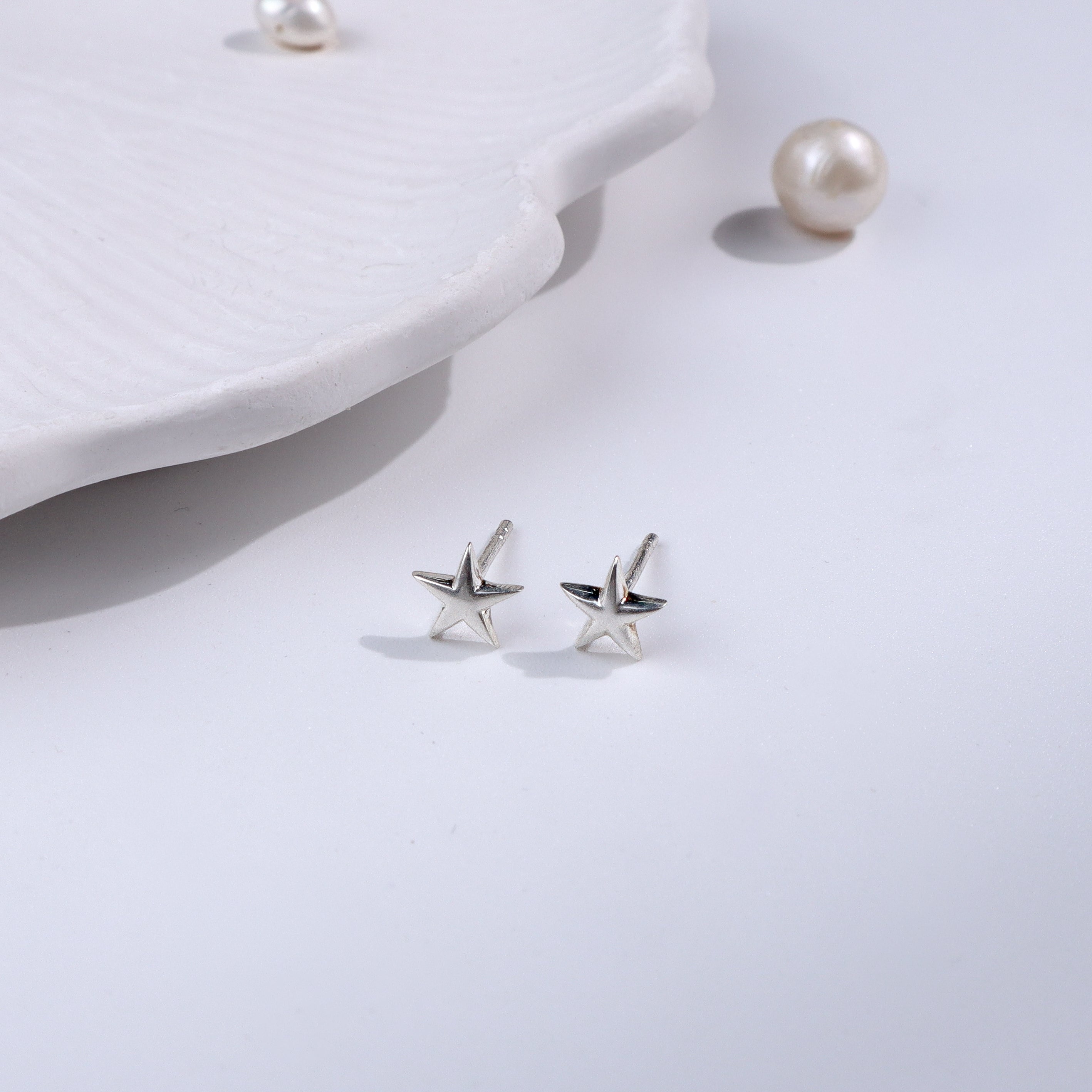 Silver starfish stud earrings on white background