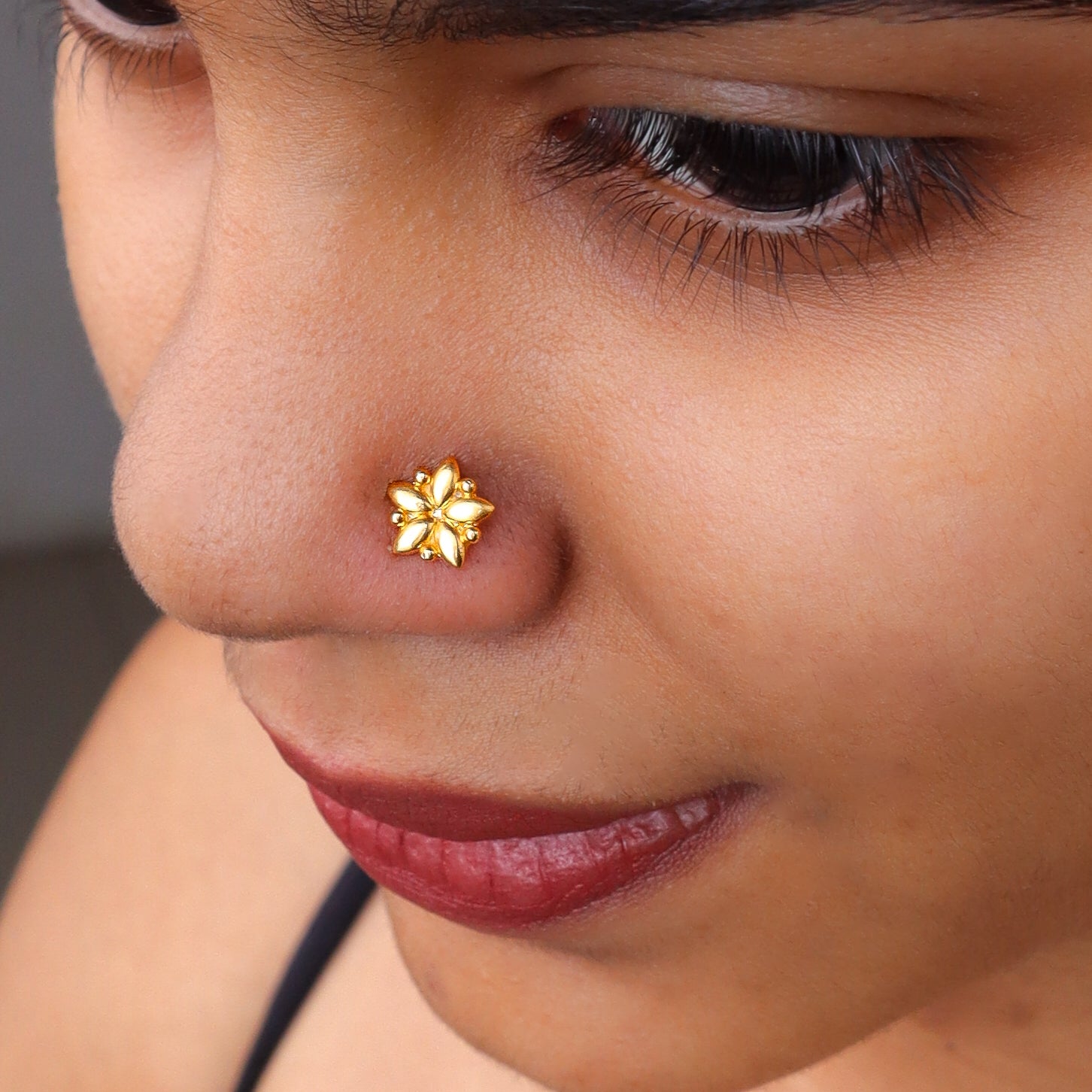 Gold floral nose pin on woman's nose