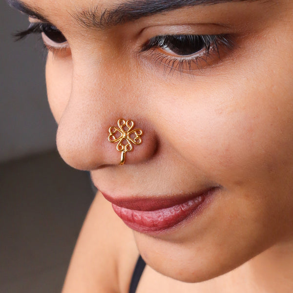 Gold-plated nose pin with intricate floral design on a woman's nose
