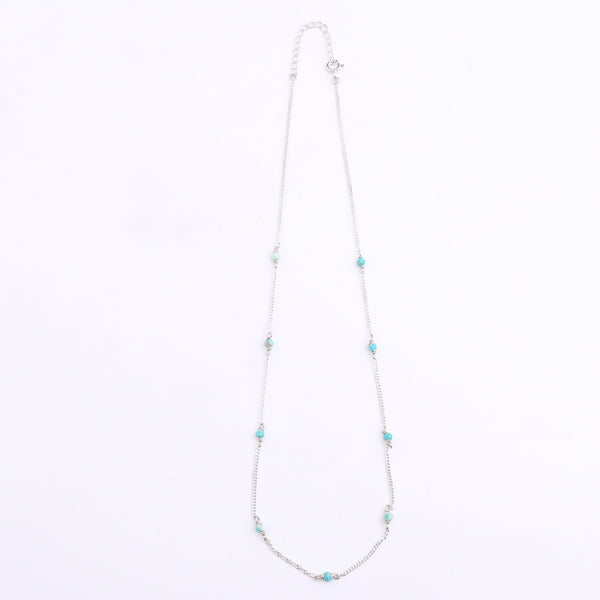 Silver chain with blue jade bead detail on white background