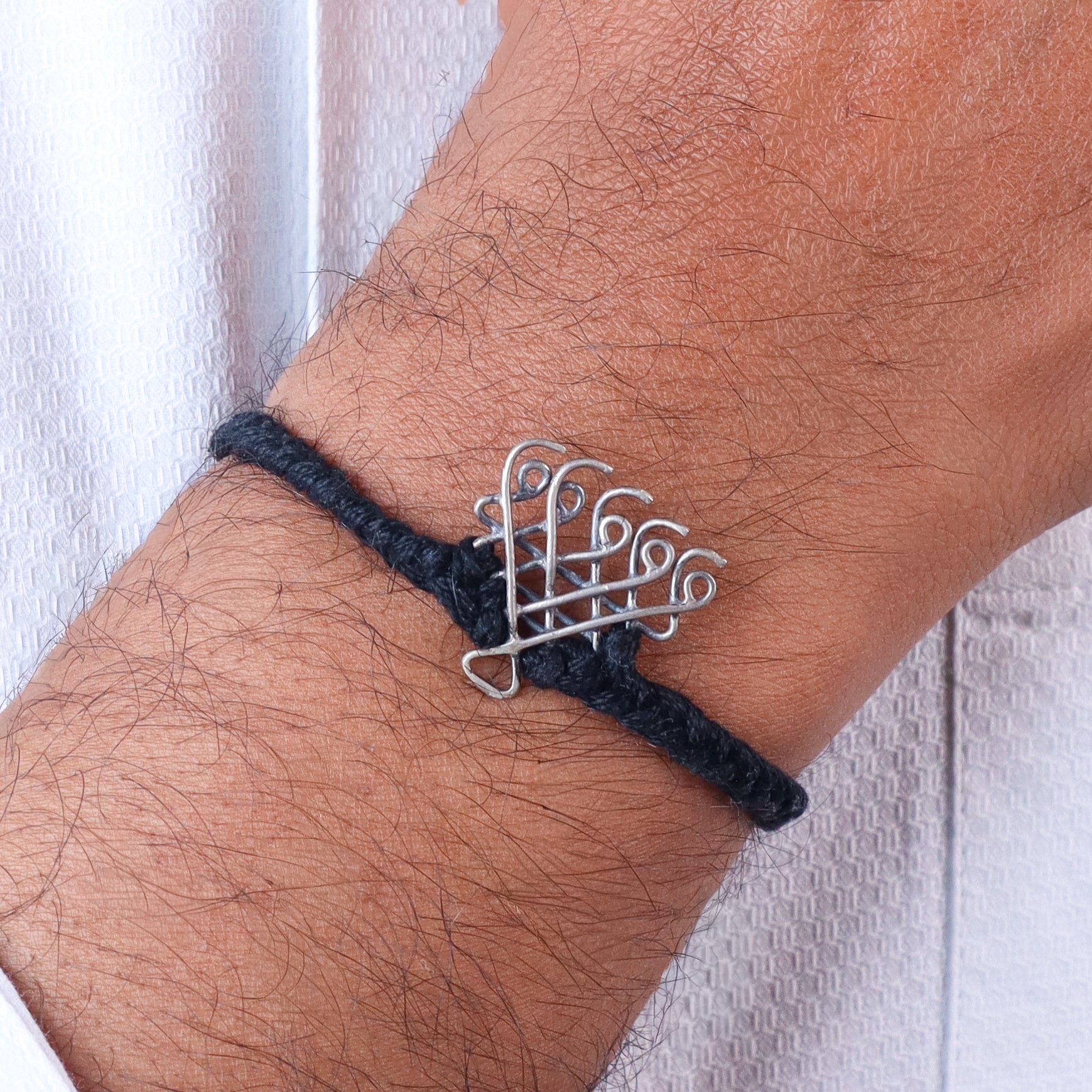 Silver Saraswati bracelet small with black thread on wrist