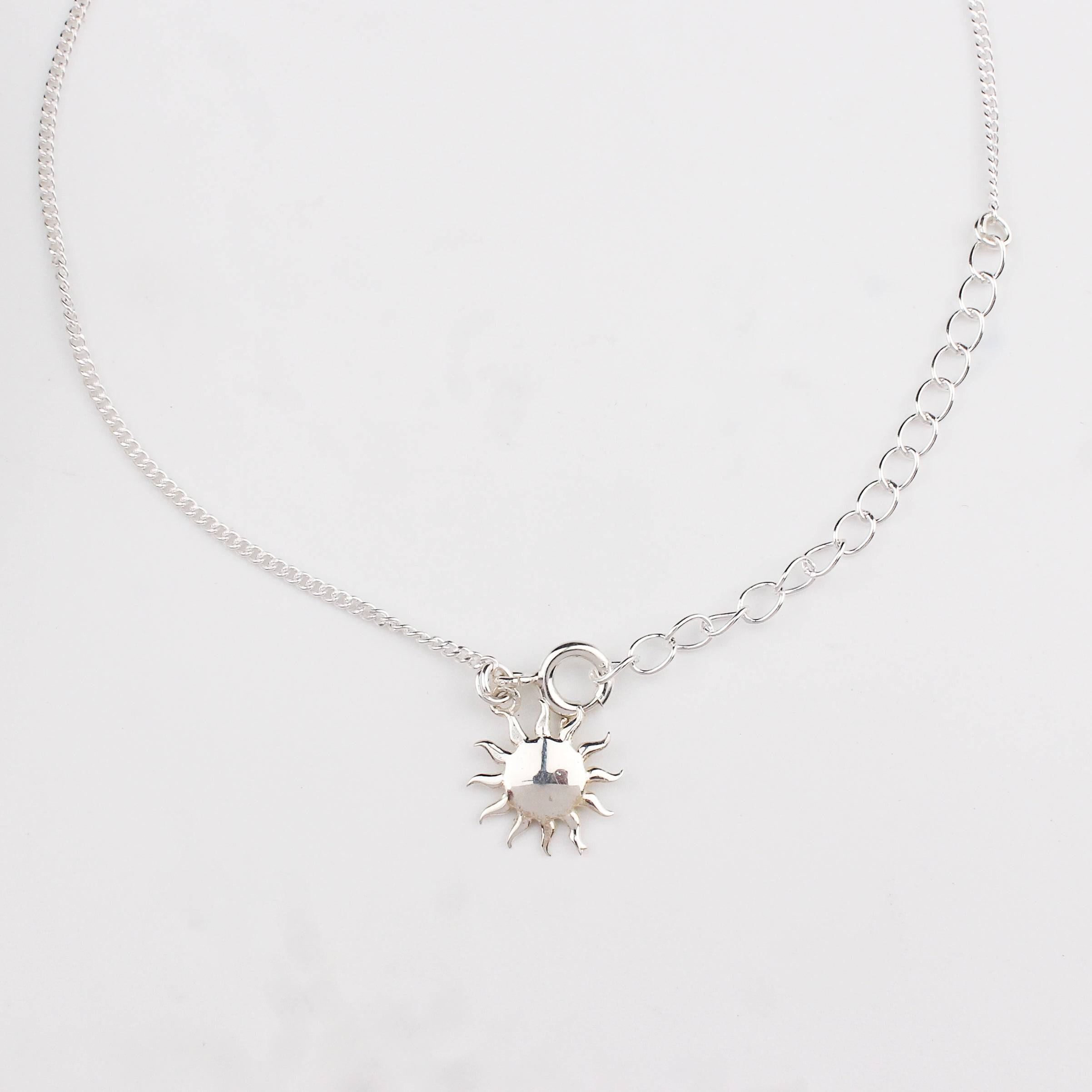 Close-up of silver sun charm anklet detailing