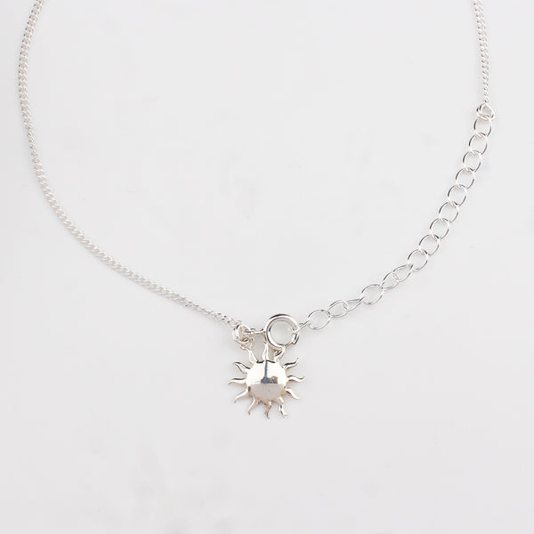 Close-up of silver sun charm anklet detailing