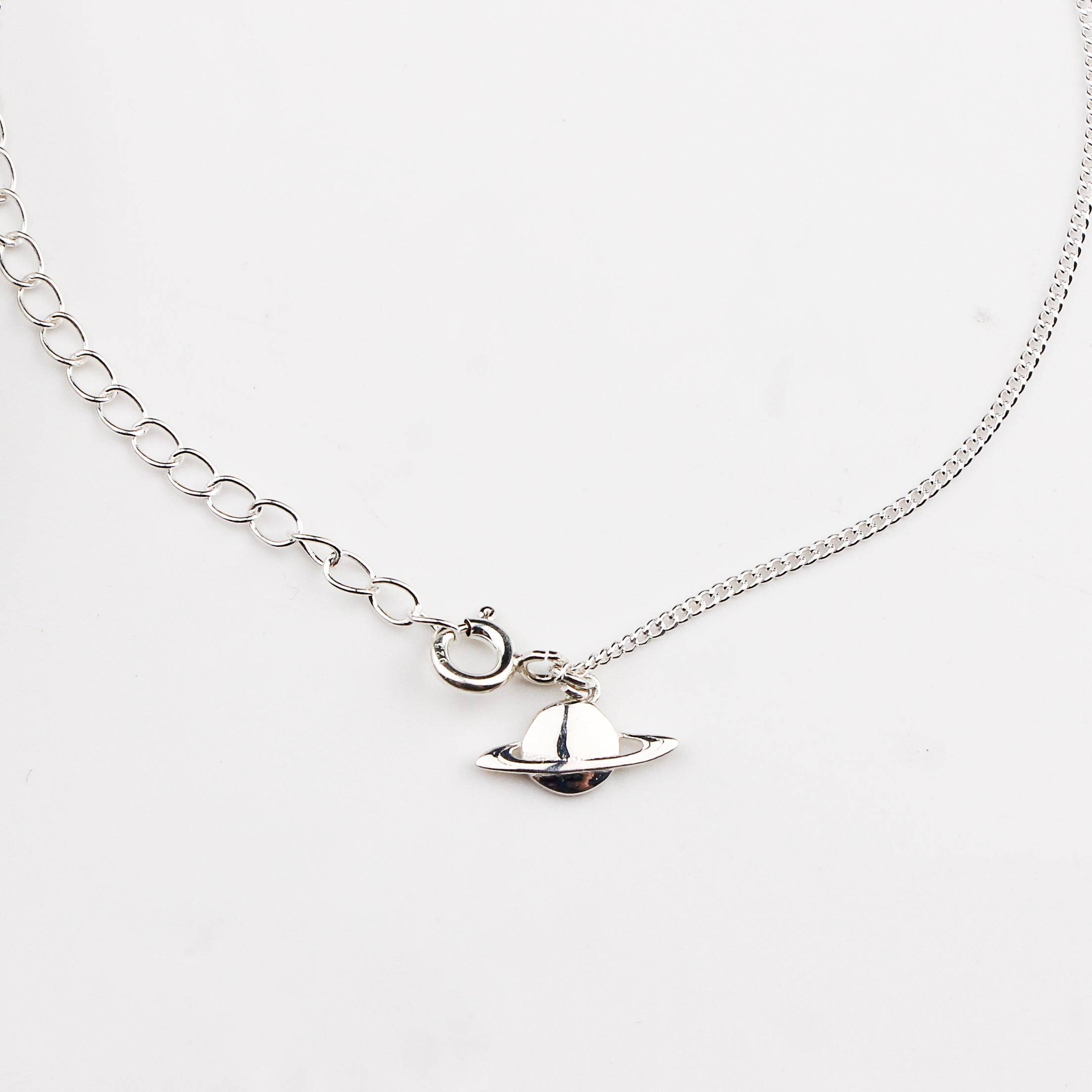 Close-up of silver planet charm anklet detailing