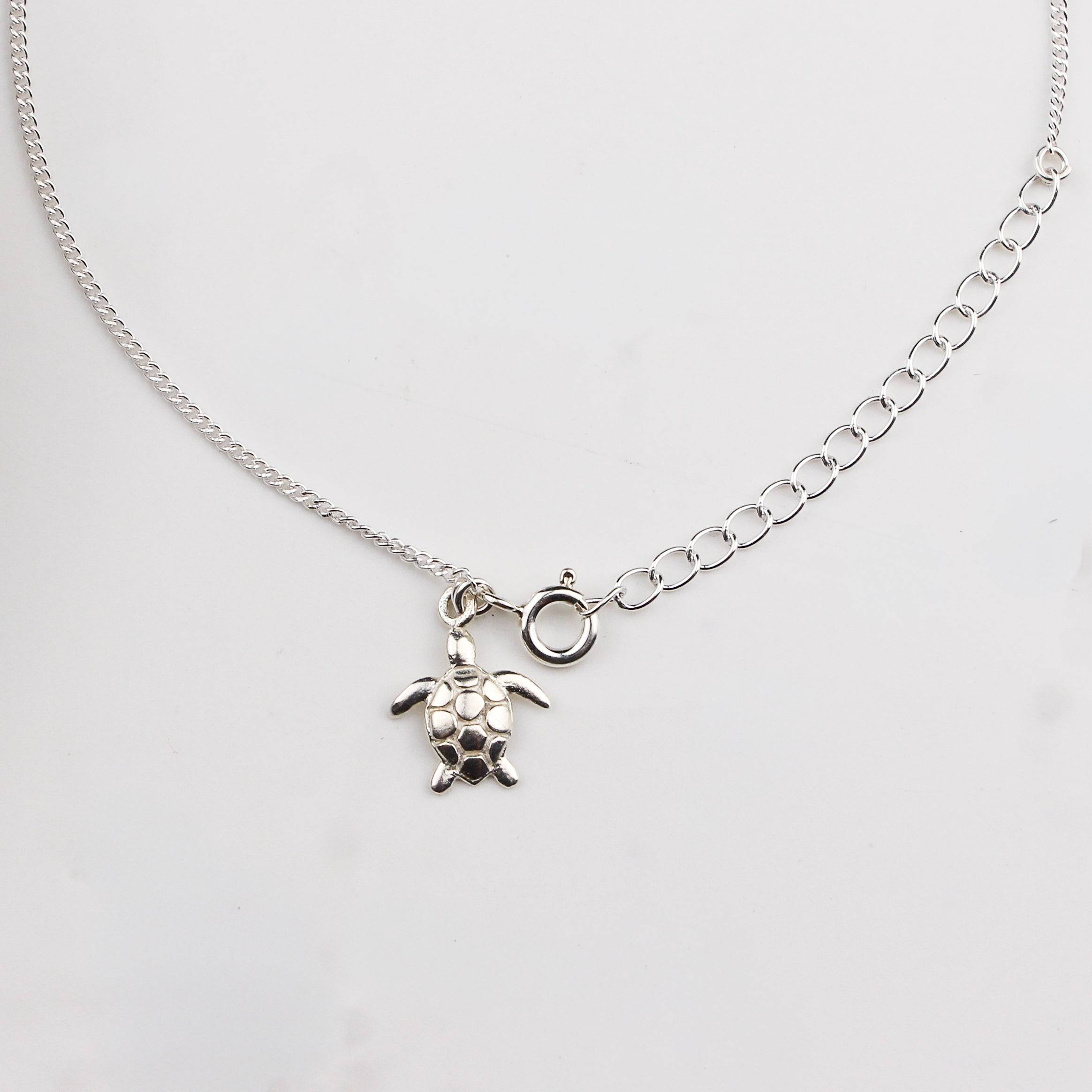 Close-up of silver turtle charm anklet detailing