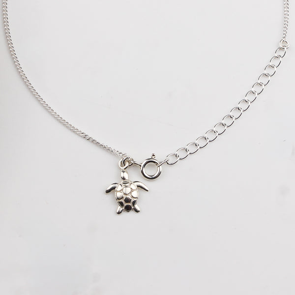 Close-up of silver turtle charm anklet detailing