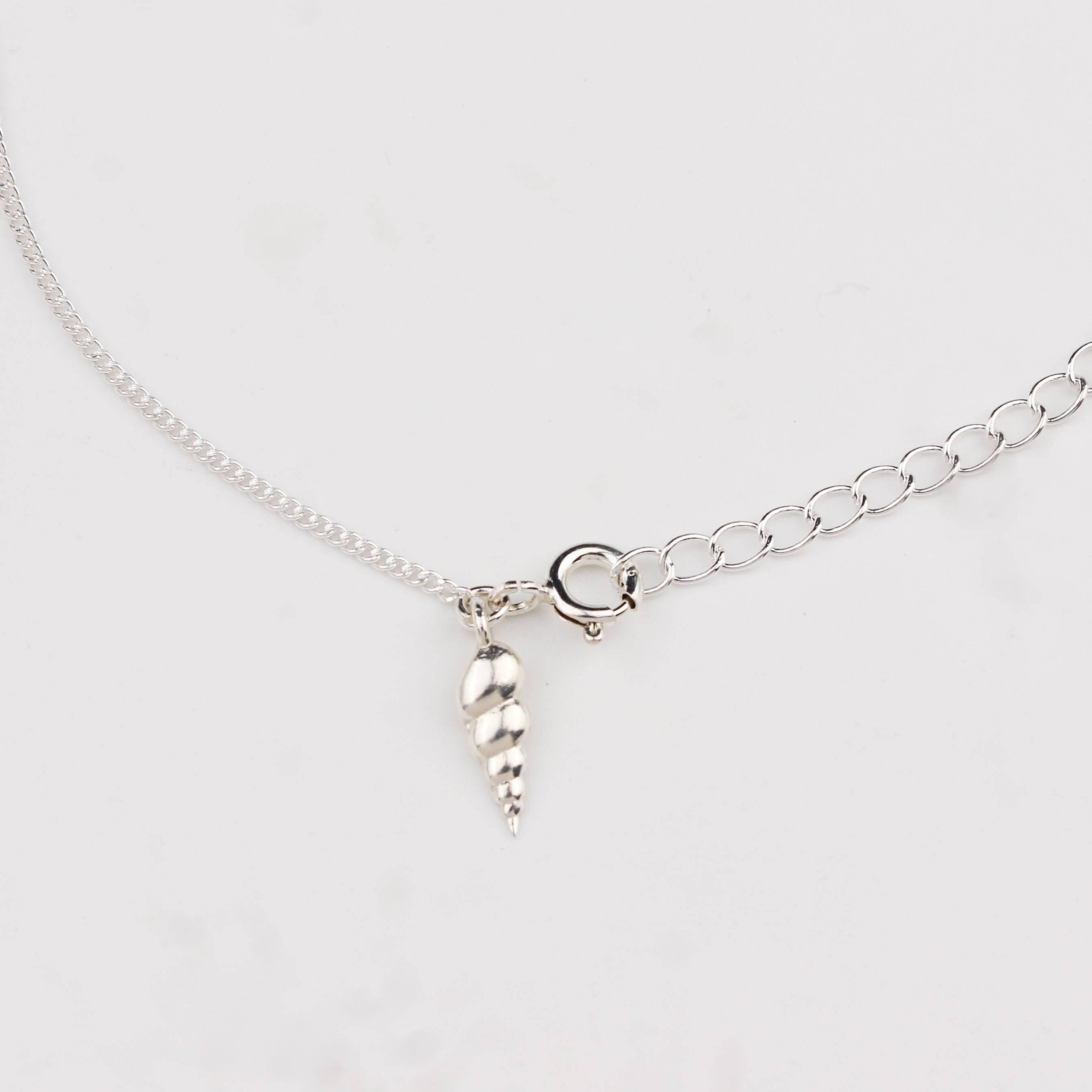 Close-up of silver auger shell charm anklet detailing
