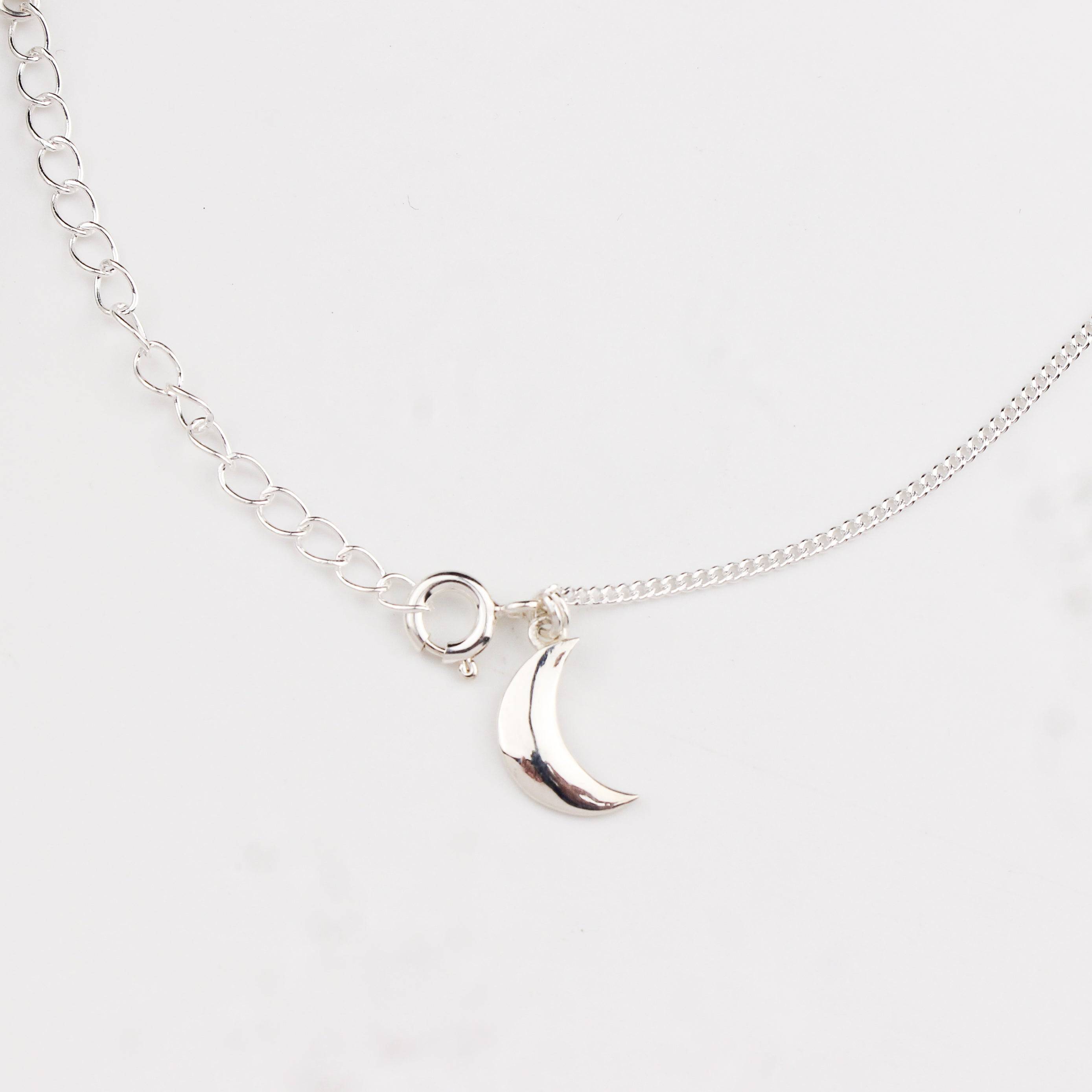 Close-up of silver crescent moon charm anklet detailing