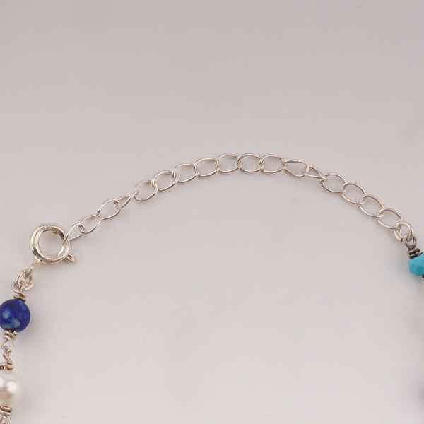 Close-up of silver chain with blue turquoise and white pearls