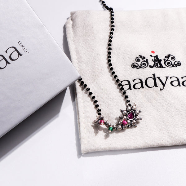 Maharashtrian silver mangalsutra with pink and green stones on Aadyaa jewelry pouch