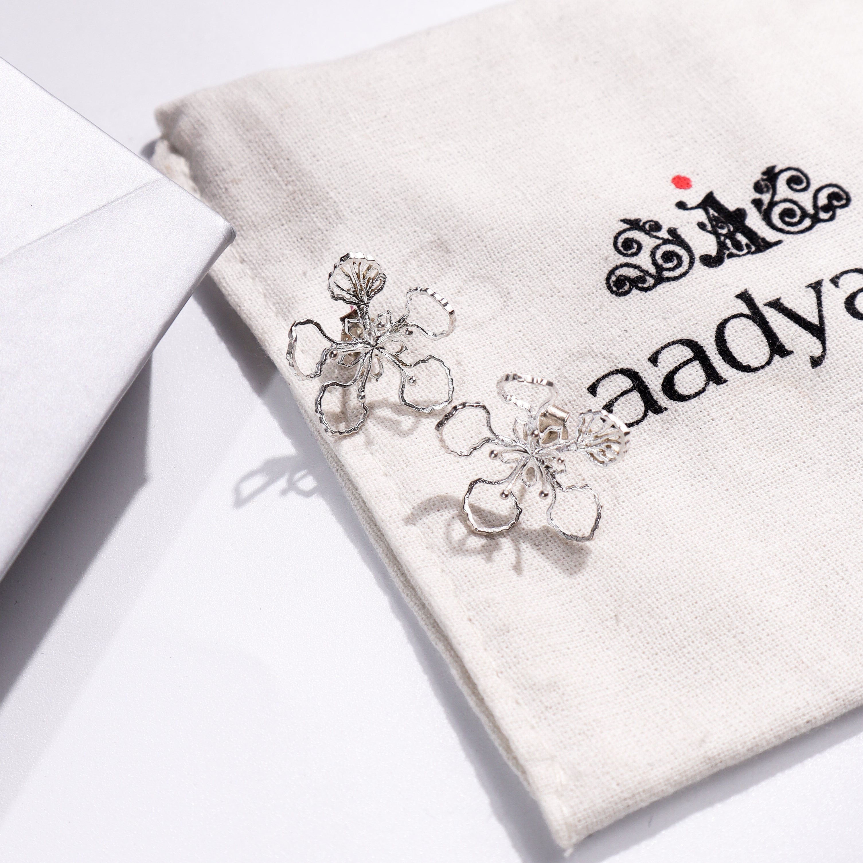 Sterling silver Gulmohar flower earrings on Aadyaa jewelry pouch