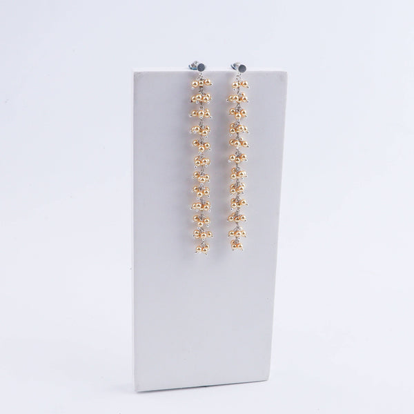Close-up of pearl dangler earrings with silver and gold beads