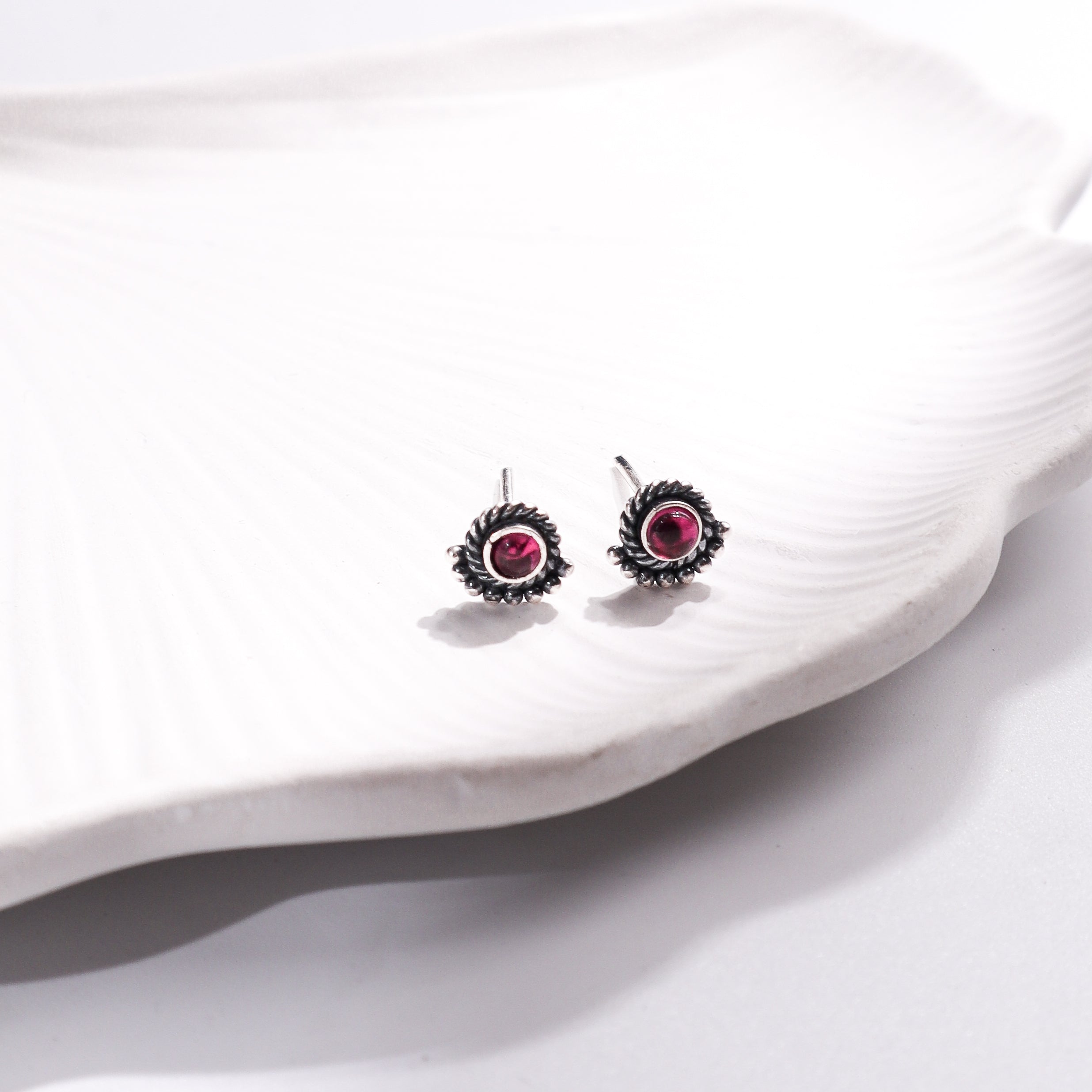 Silver earrings with pink stones on white shell
