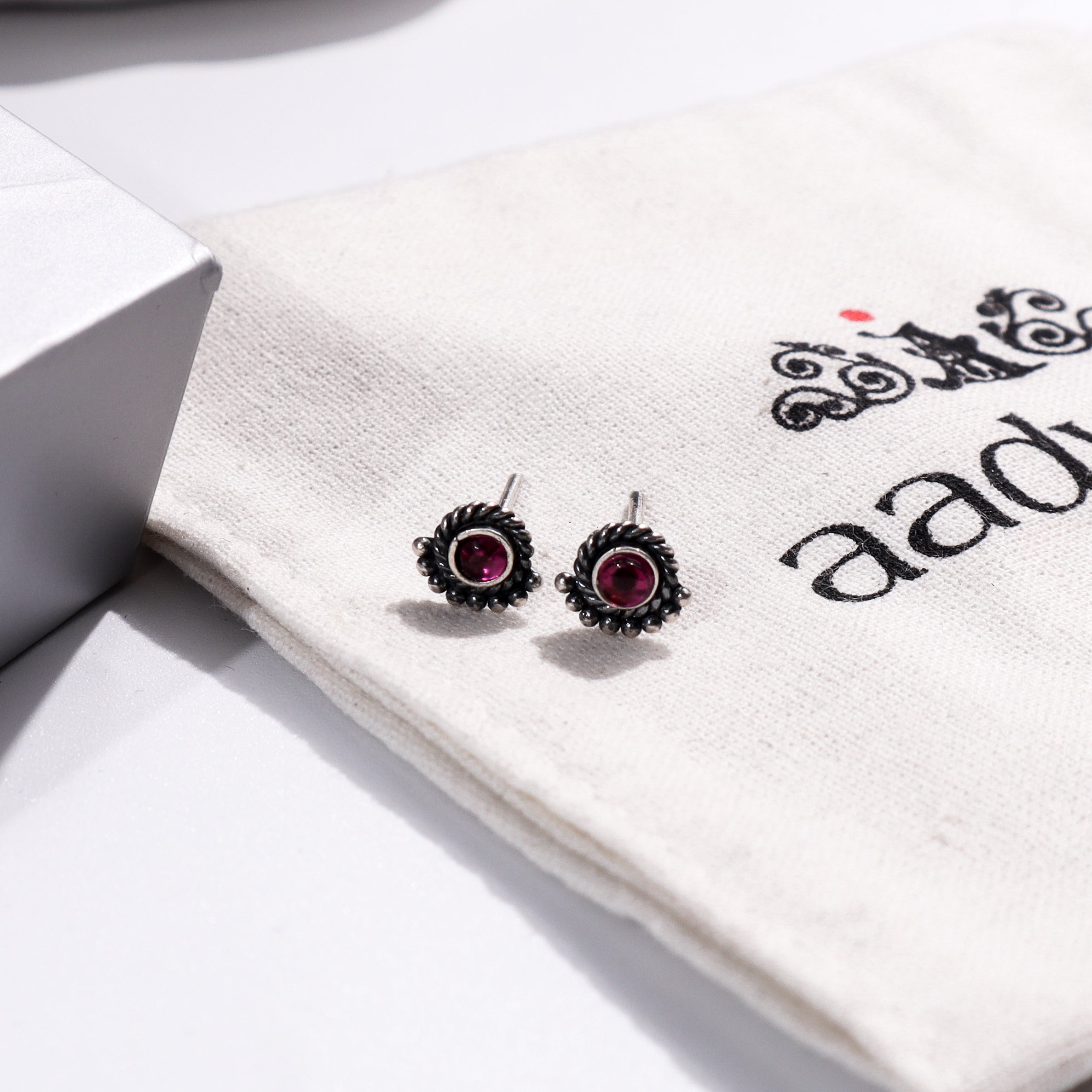Silver earrings with red gemstones on Aadyaa jewelry pouch