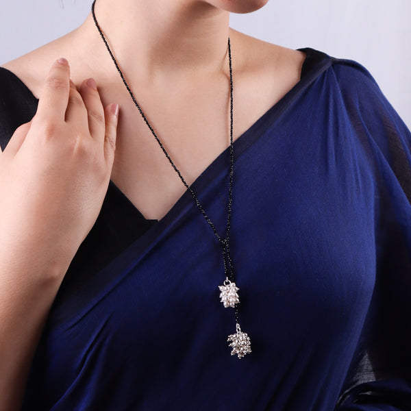 Black beaded mangalsutra with floral pendant on blue fabric