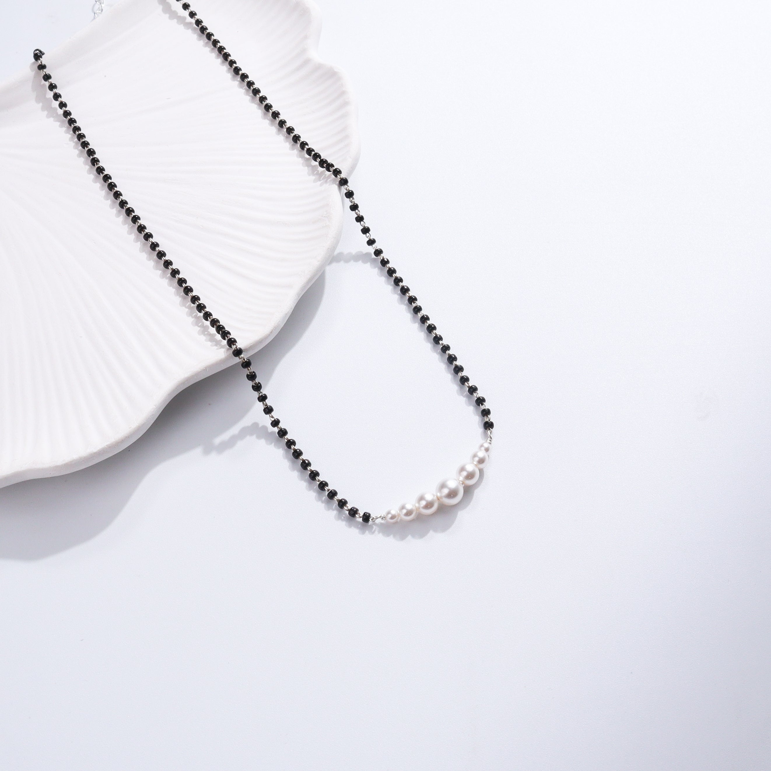 Minimal Pearls Silver Mangalsutra with black beads and pearl accents on white ceramic dish