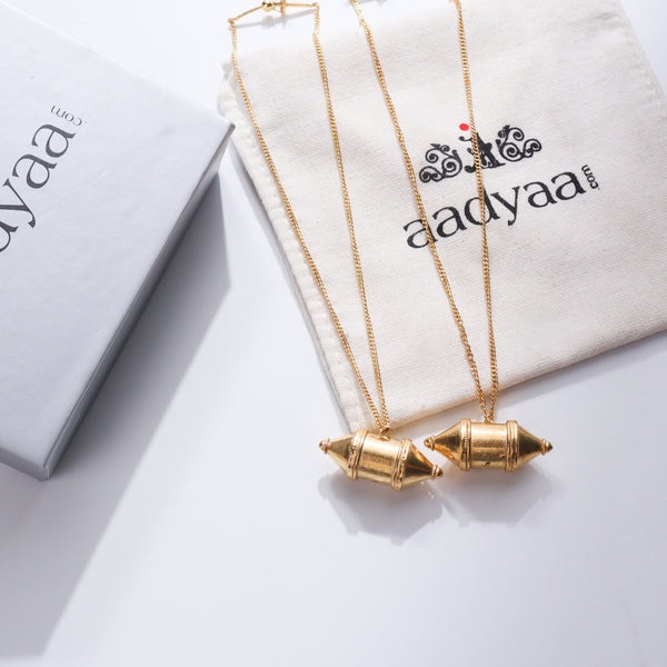 Gold Kashmir Dejhoor earrings with traditional design on a jewelry pouch