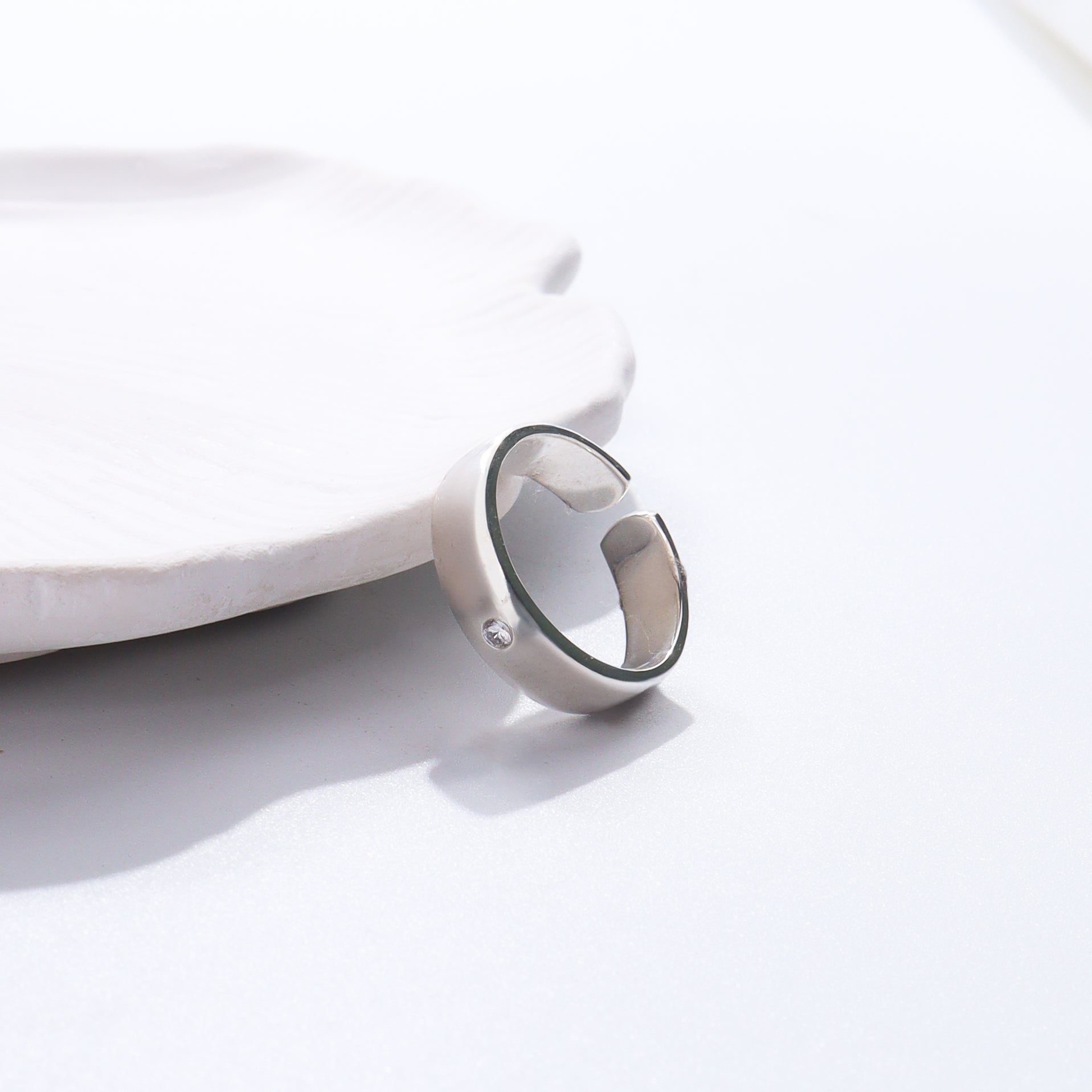 Silver ring with heart design on white ceramic dish