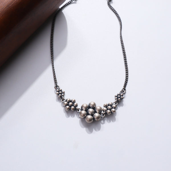Silver necklace with beaded design and floral pendant
