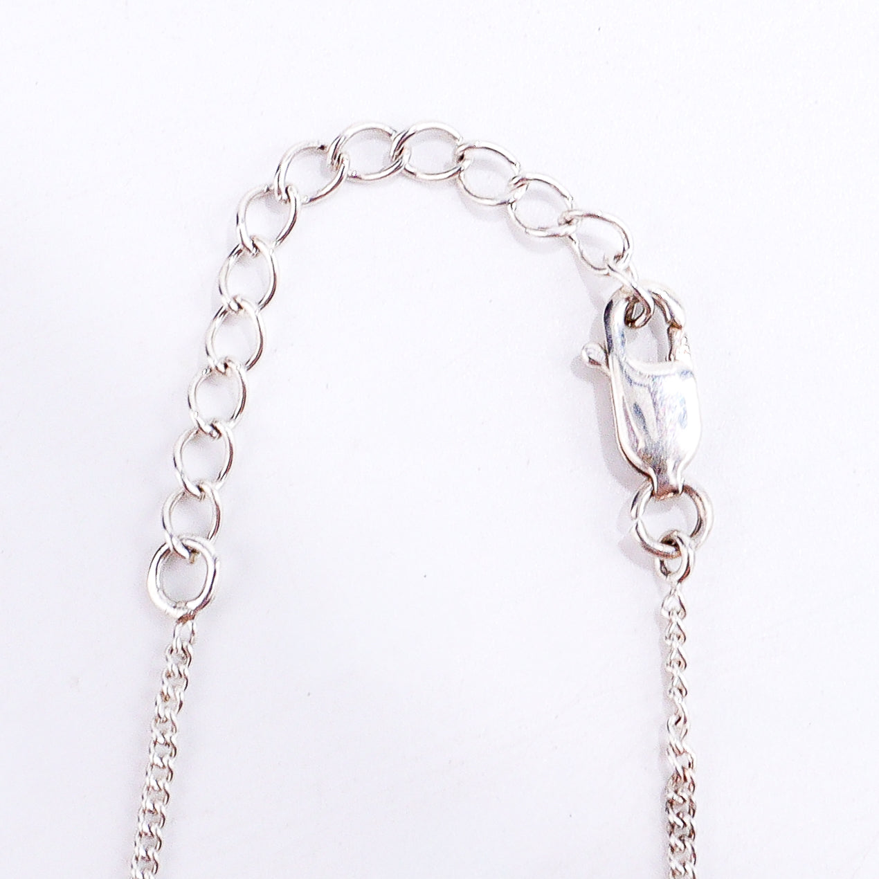 Flat-lay silver necklace with mother pendant on neutral background