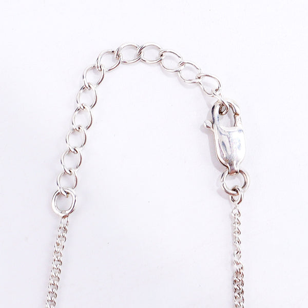 Flat-lay silver necklace with mother pendant on neutral background