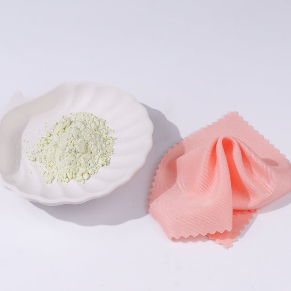 White dish with green powder and pink cloth on a white background