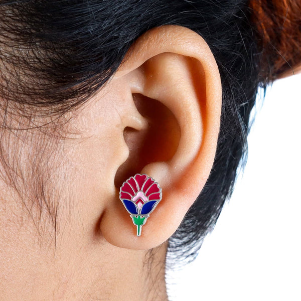 Close-up of enamel flower earrings worn on ear with colorful floral motif