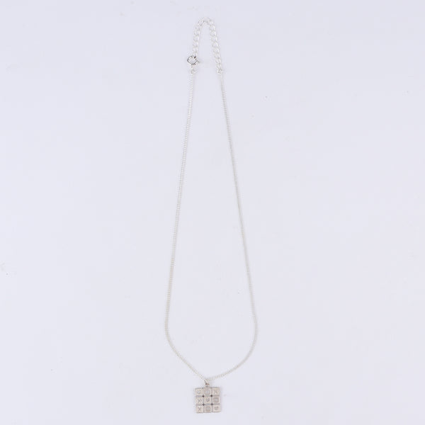 Close-up of tic tac toe grid detailing on big silver pendant