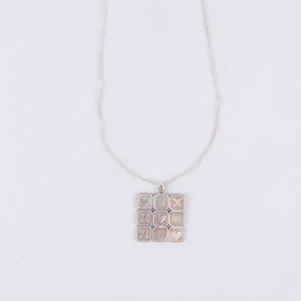 Close-up of tic tac toe grid detailing on silver pendant